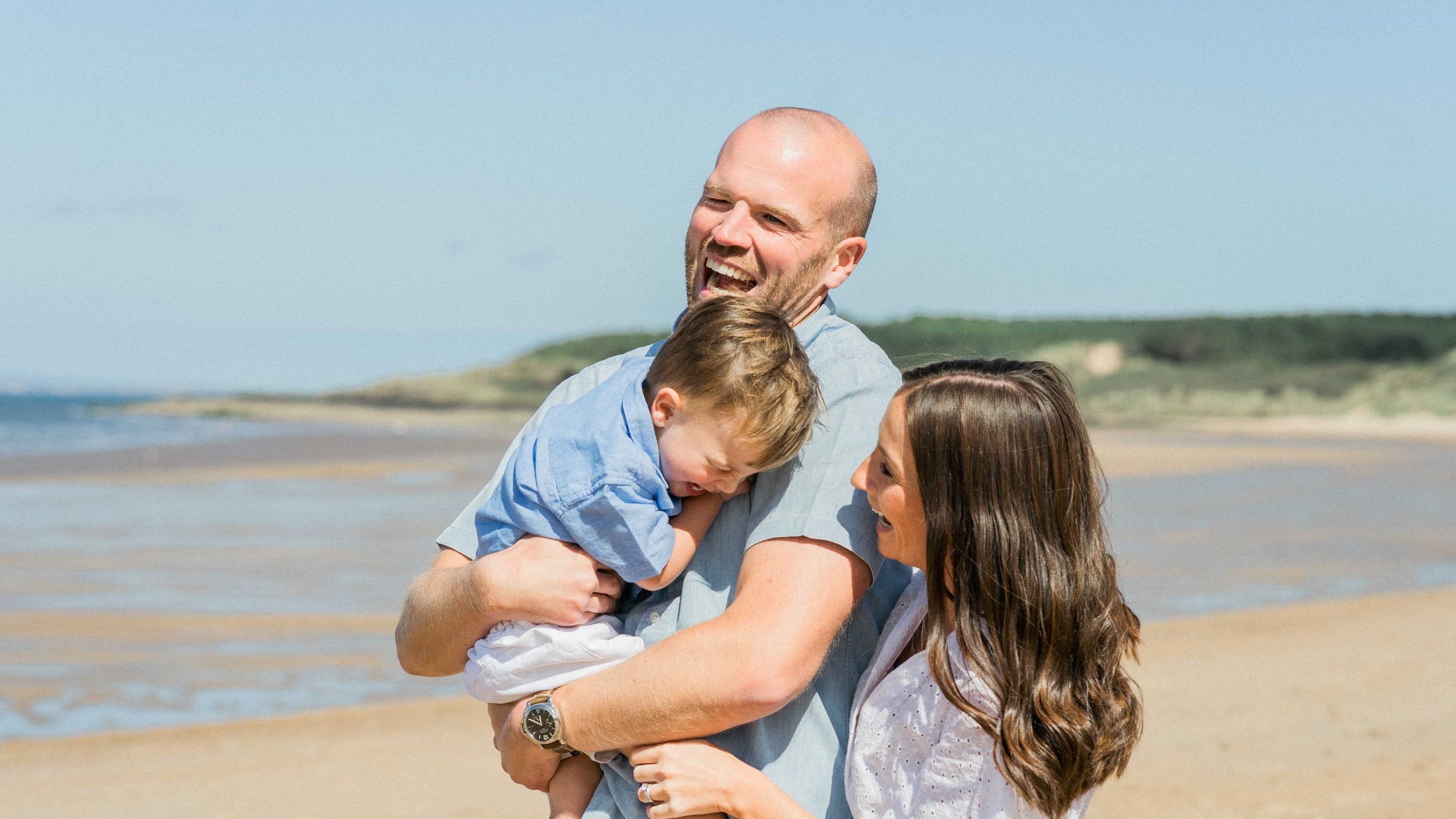 Family of three on a beach with a clear sky