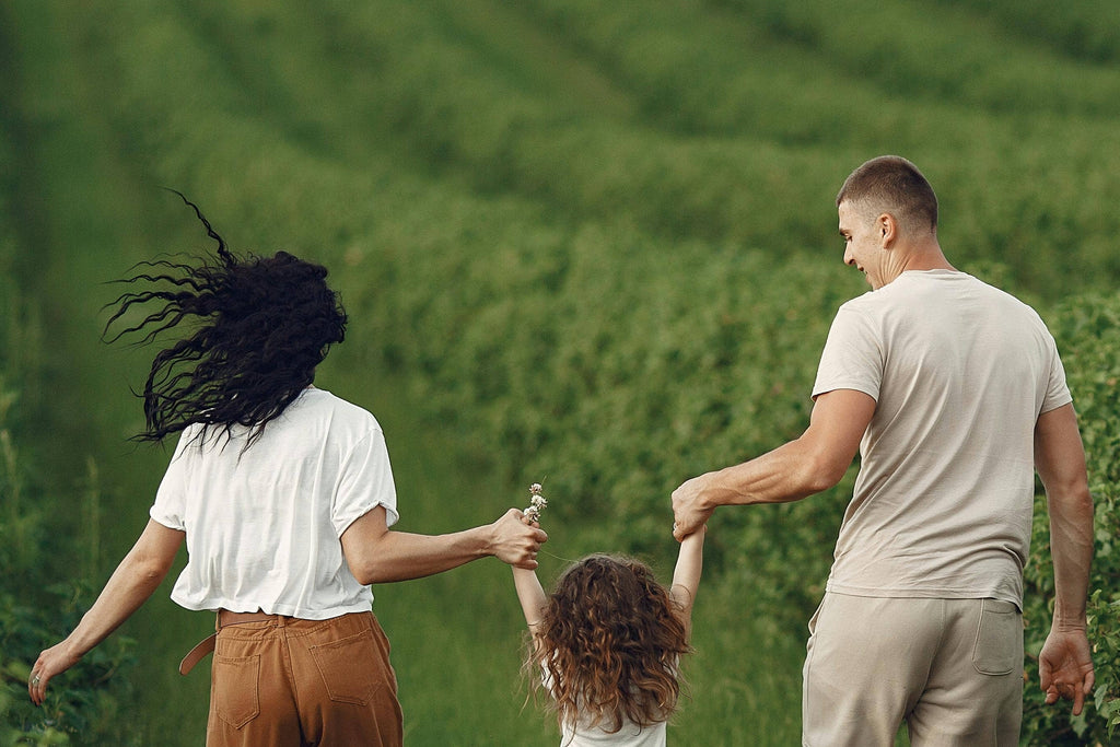 Family of three walking together in a grassy field