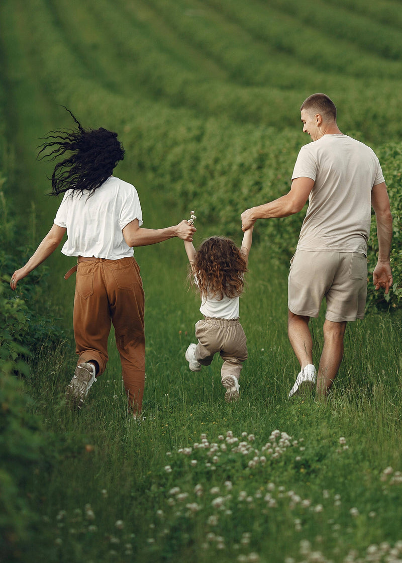 Family of three walking together in a grassy field